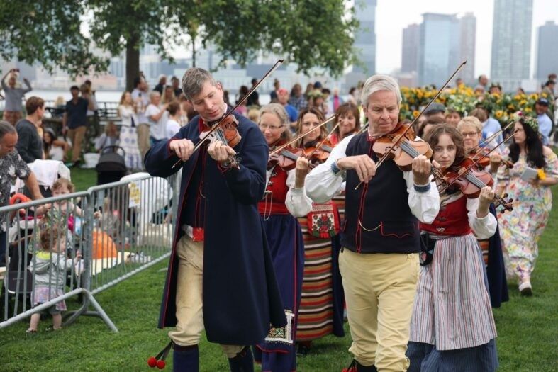Folkmusiker spelar fiol i färgstarka traditionella kläder i en stadspark
